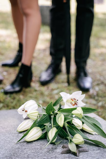 A bouquet of white lilies with large, open petals and prominent stamens, arranged with long, slender green leaves. The flowers are freshly cut, displaying smooth, waxy petals and sturdy stems, with so
